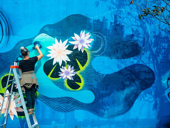 Female mural artist in flow state creating wall art